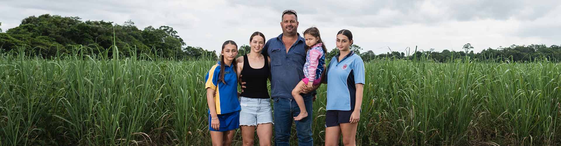 The Di Mauro family standing in front of a crop of sugarcane