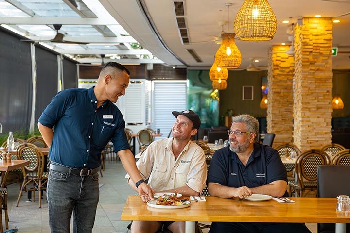 A restaurant worker serves Nathan and Angelo a plate for delicious crayfish.